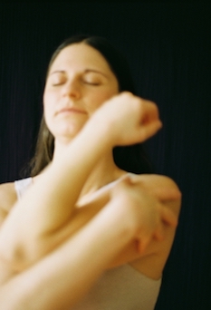 eine doula in Berlin, die sich in einer embodiment-Übung eine Umarmung gibt. Ihr Augen sind geschlossen