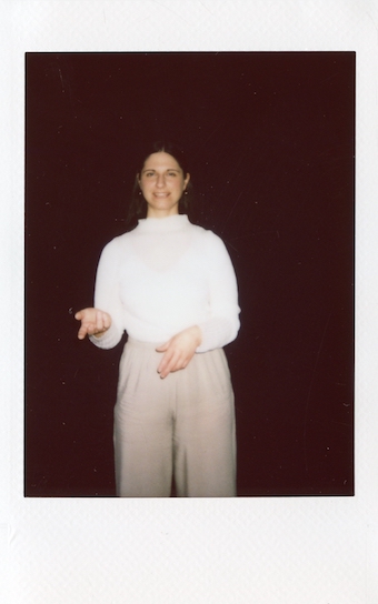 Doula und Geburtsbegleiterin in Berlin, sie trägt helle Kleidung und schaut direkt in die Kamera, ihre Hände formen eine Geste als würde sie sprechen